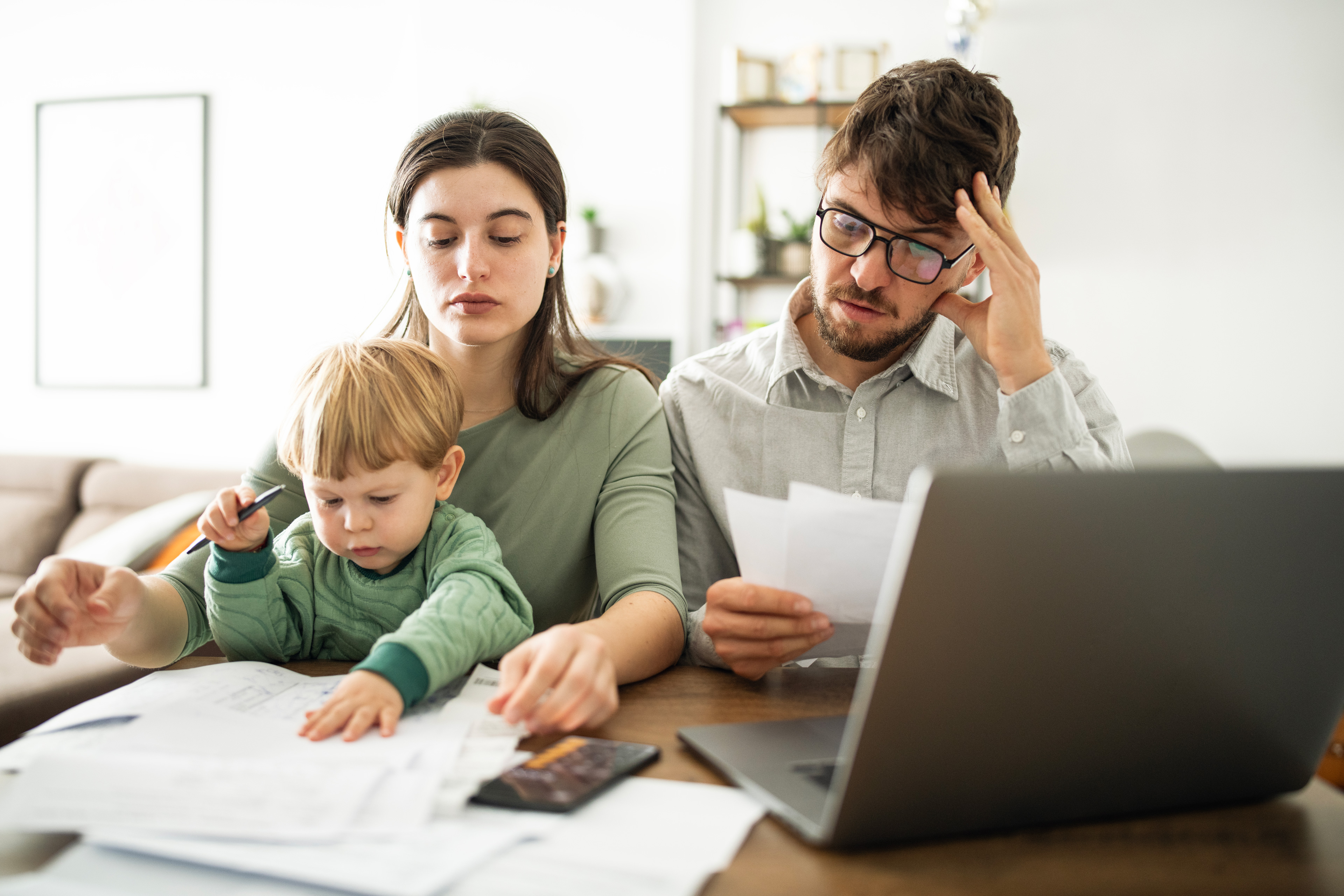 Zwei Eltern mit einem Kleinkind kümmern sich um Anträge.