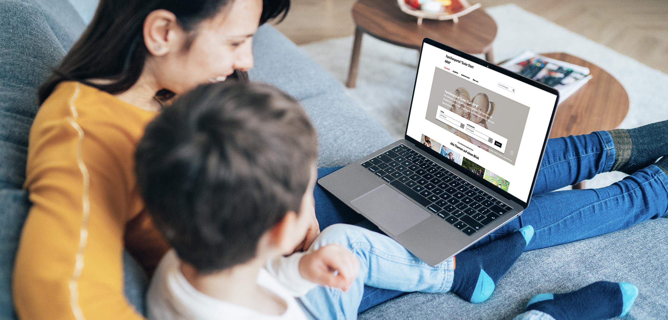 Eine Mutter sitzt mit dem Sohn auf dem Sofa uns sucht im Internet nach kommunalen Angeboten.