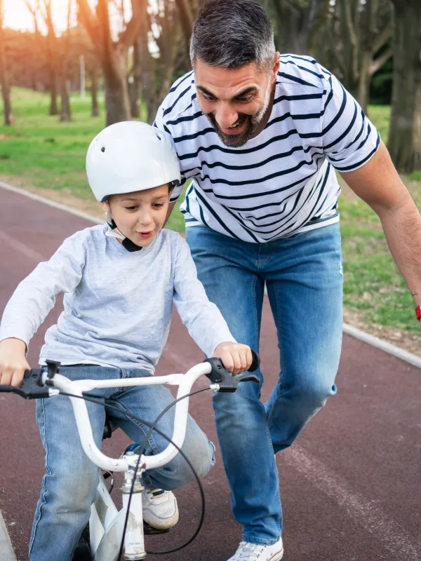 Vater hilft Kind beim Fahrrad fahren