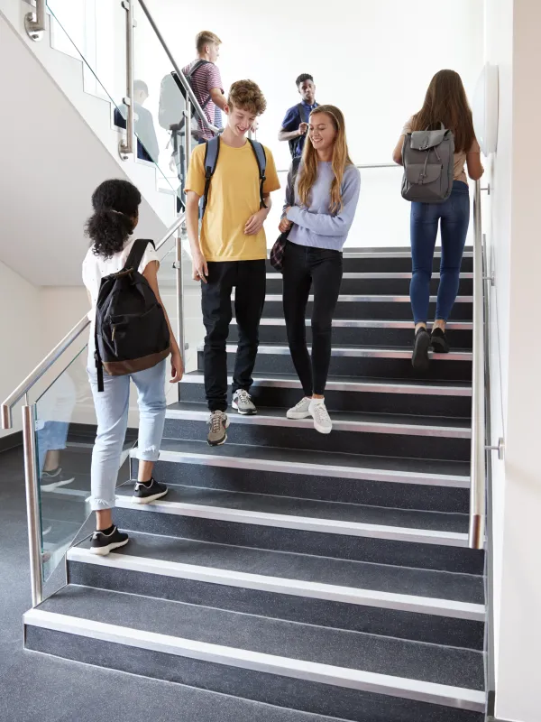 Schülerinnen und Schüler auf einer Treppe im Schulgebäude.