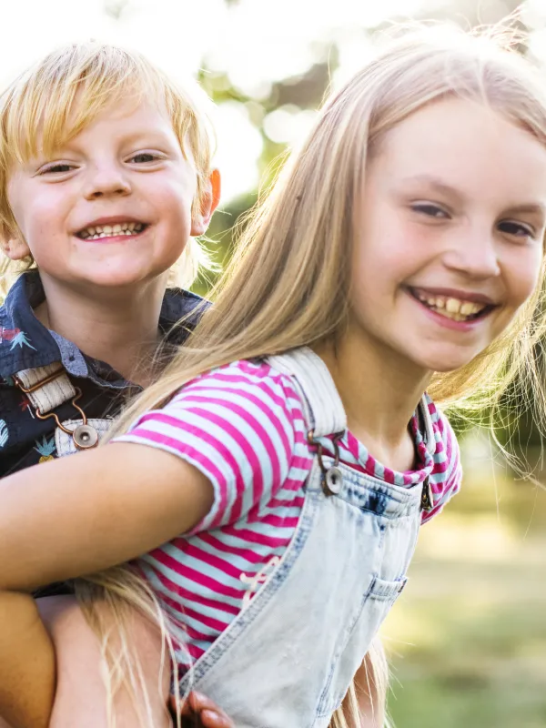 Ein Mädchen trägt ihren kleinen Bruder huckepack.