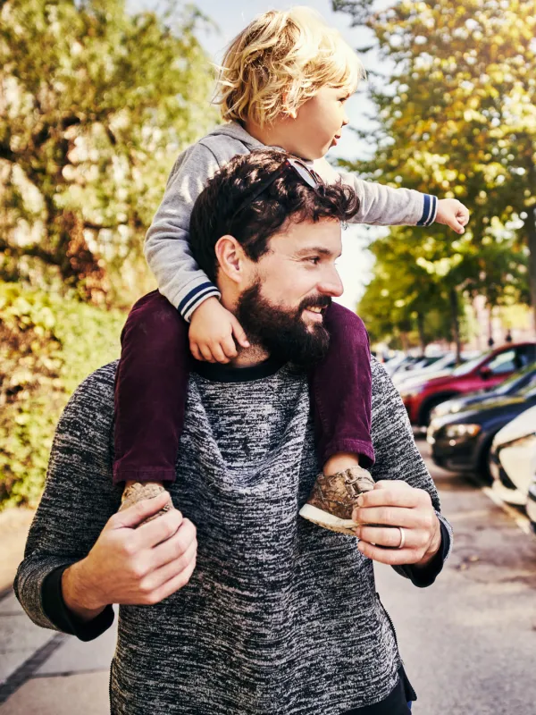 Zwei Eltern tragen ihre beiden Kleinkinder bei einem Ausflug durch die Stadt.