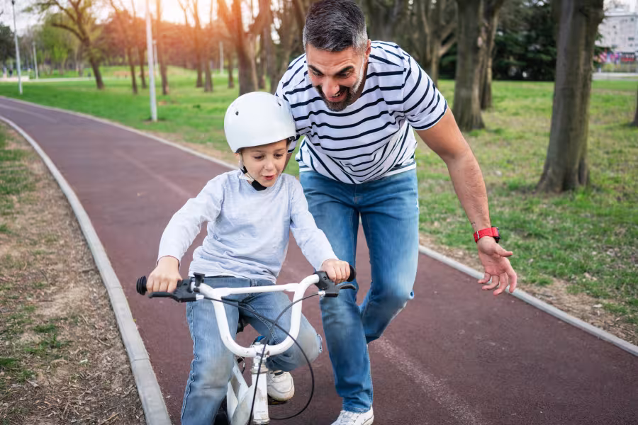 Vater hilft Kind beim Fahrrad fahren