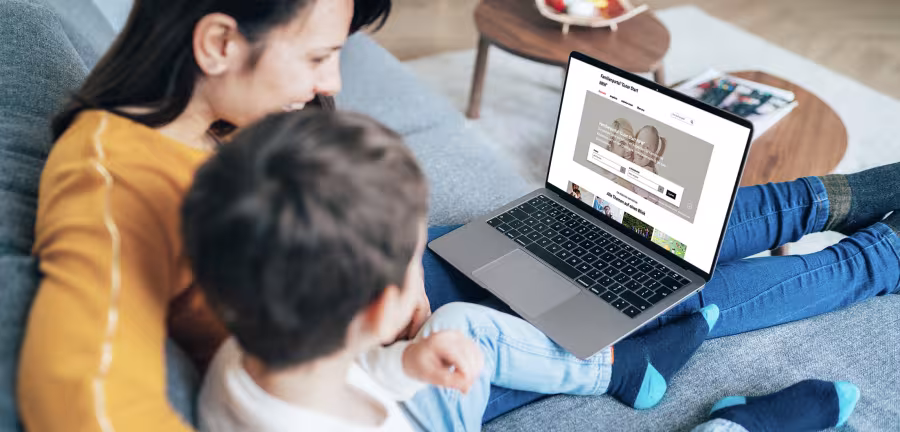 Eine Mutter sitzt mit dem Sohn auf dem Sofa uns sucht im Internet nach kommunalen Angeboten.