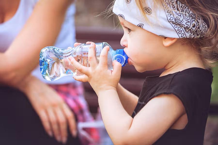 Ein kleines Kind trinkt aus einer Wasserflasche.