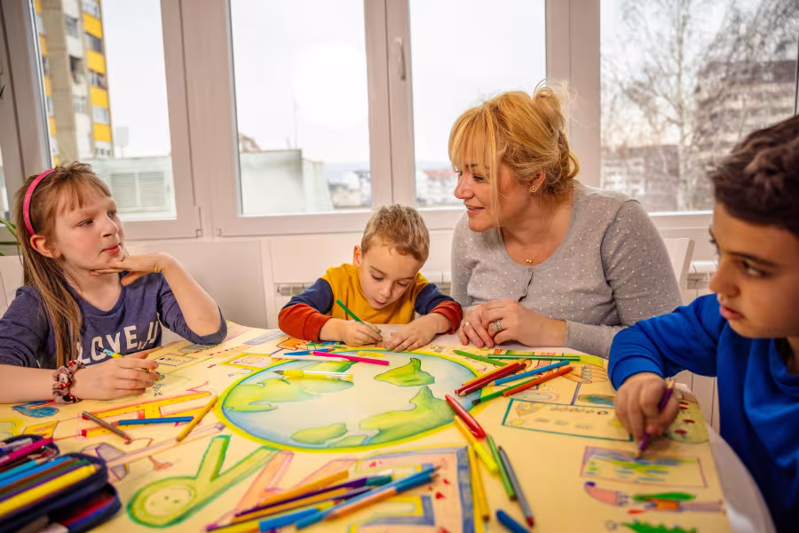 Kinder in der Nachmittagsbetreuung basteln gemeinsam an einem Plakat.